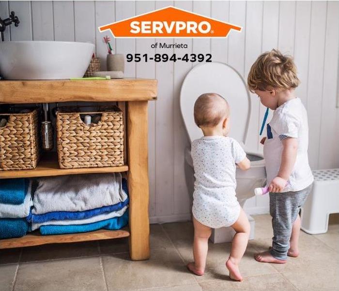 Two small children are throwing items into the toilet.