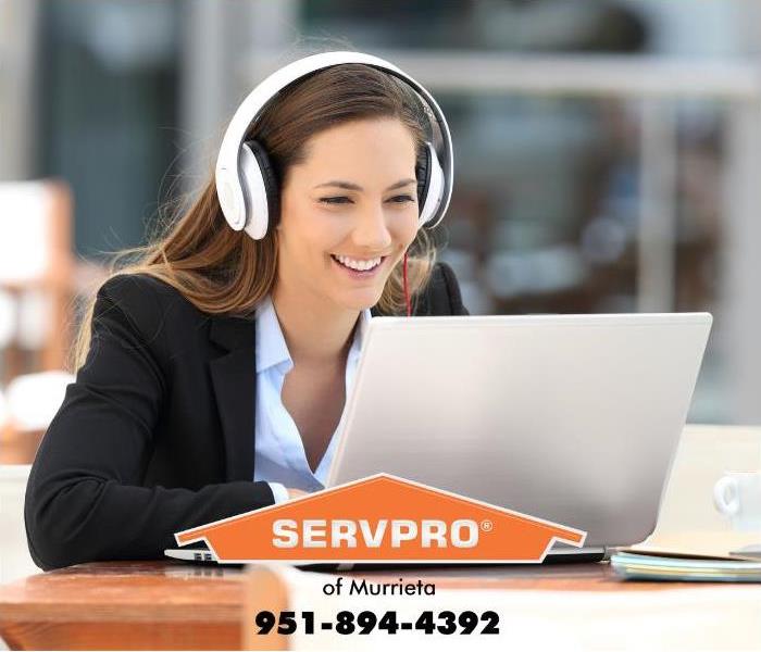 An employee is using a laptop computer with headphones on.