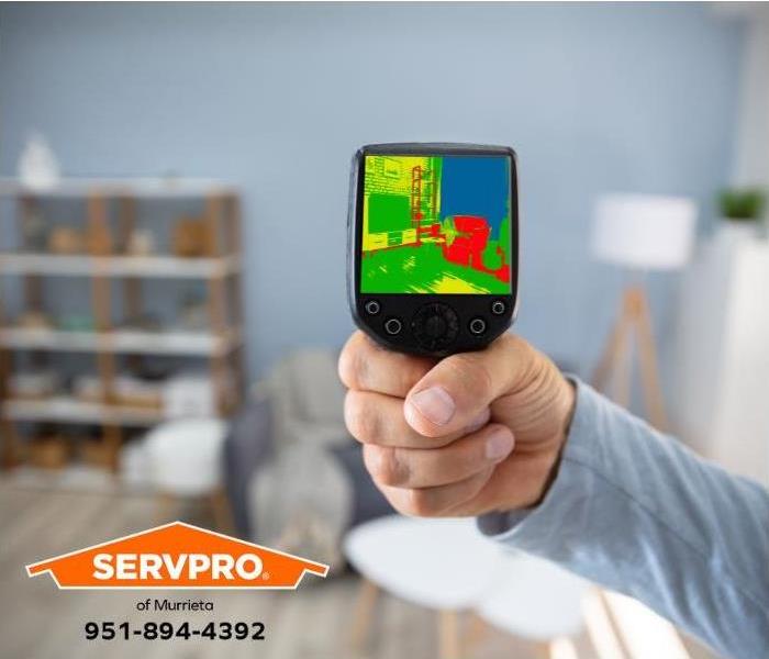A person uses an infrared camera to locate the source of water damage in a home.
