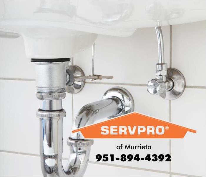 Plumbing pipes underneath a sink are shown.