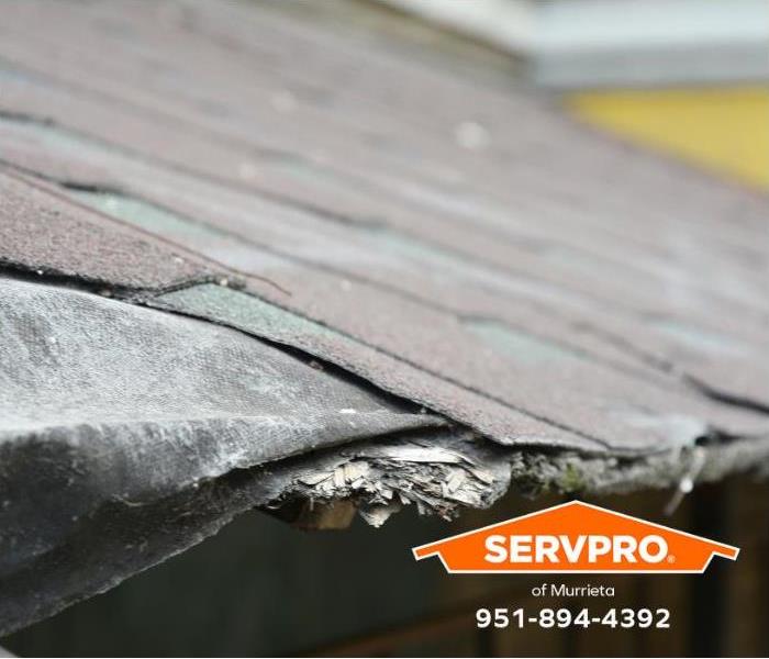 A roof shows damaged shingles. 