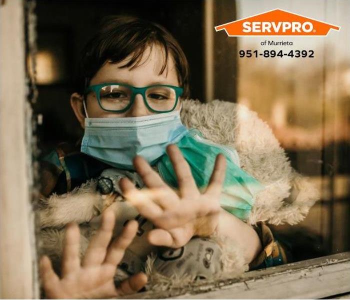 A sick child looks out the window of their home.