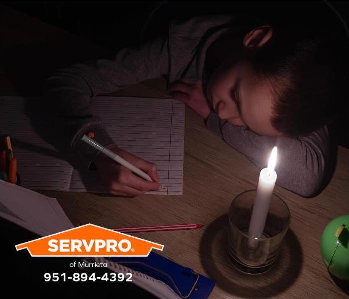 A student is studying by candlelight during a power outage.