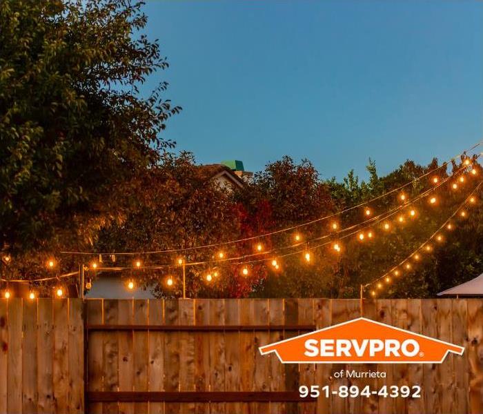 Strings of outdoor party lights light up a backyard.