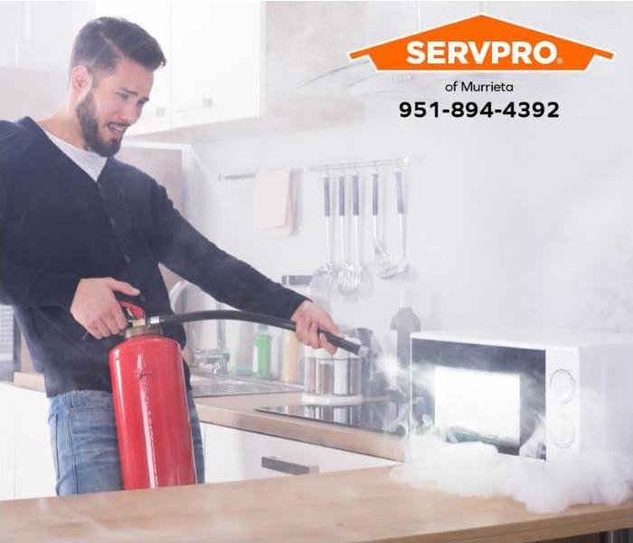 A person uses a fire extinguisher to put out a fire in a microwave oven.