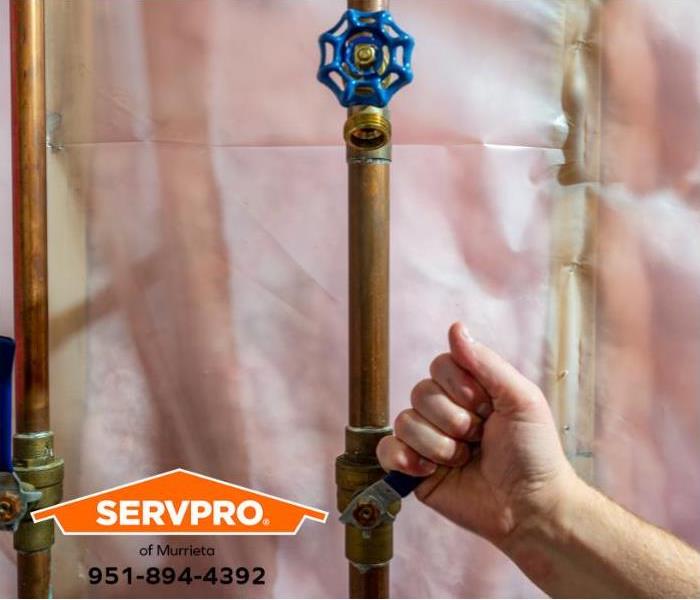 A person shuts off the main water supply to prevent more water damage from a broken pipe.
