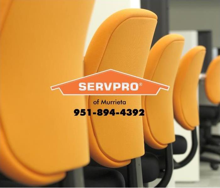 The backs of orange upholstered chairs are shown in an office setting.  