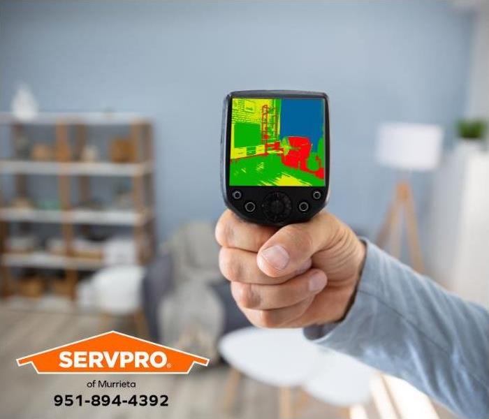 A person uses an infrared camera to locate the source of water damage in a home.